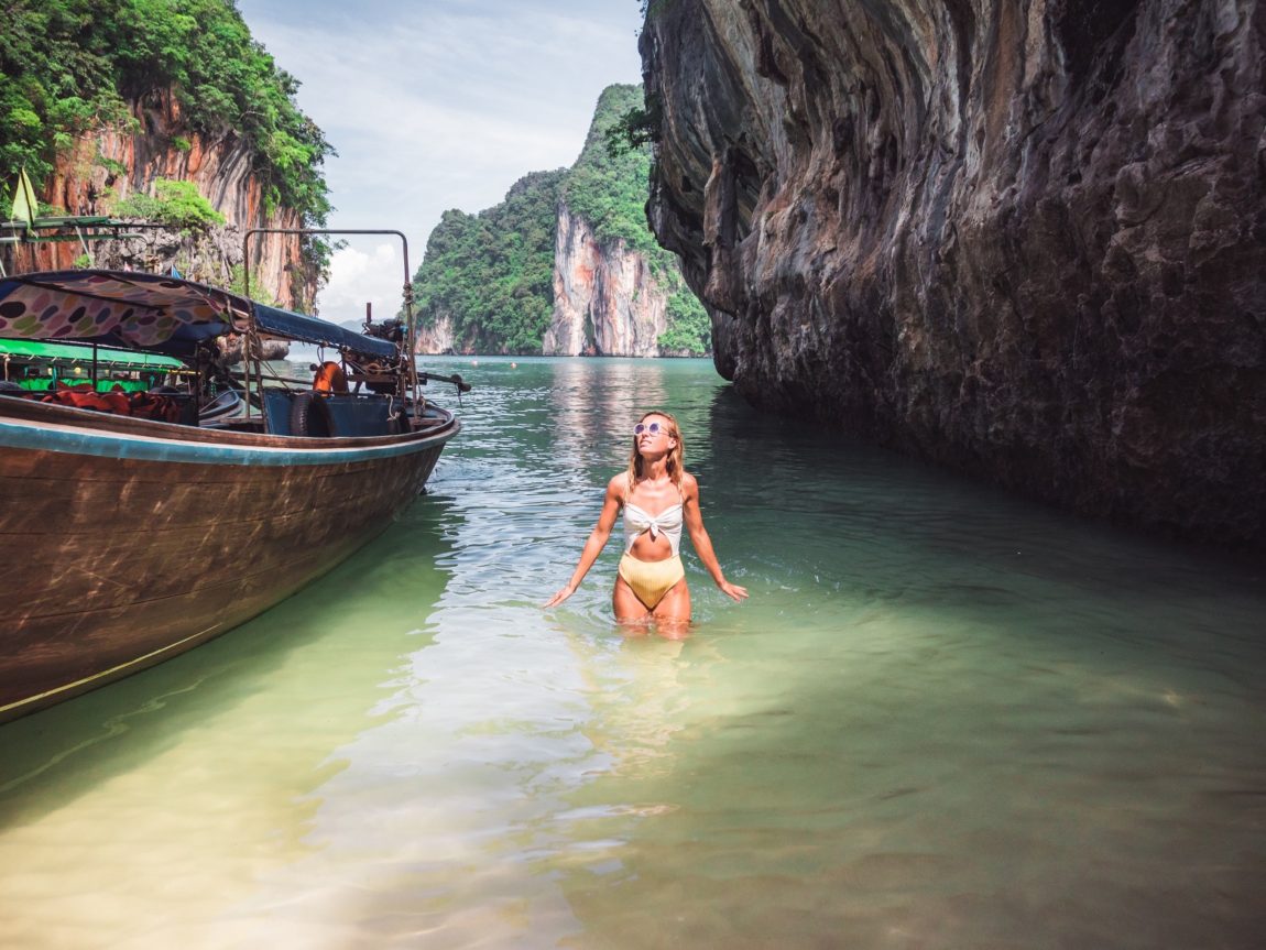 A woman standing in the ocean next to a small boat