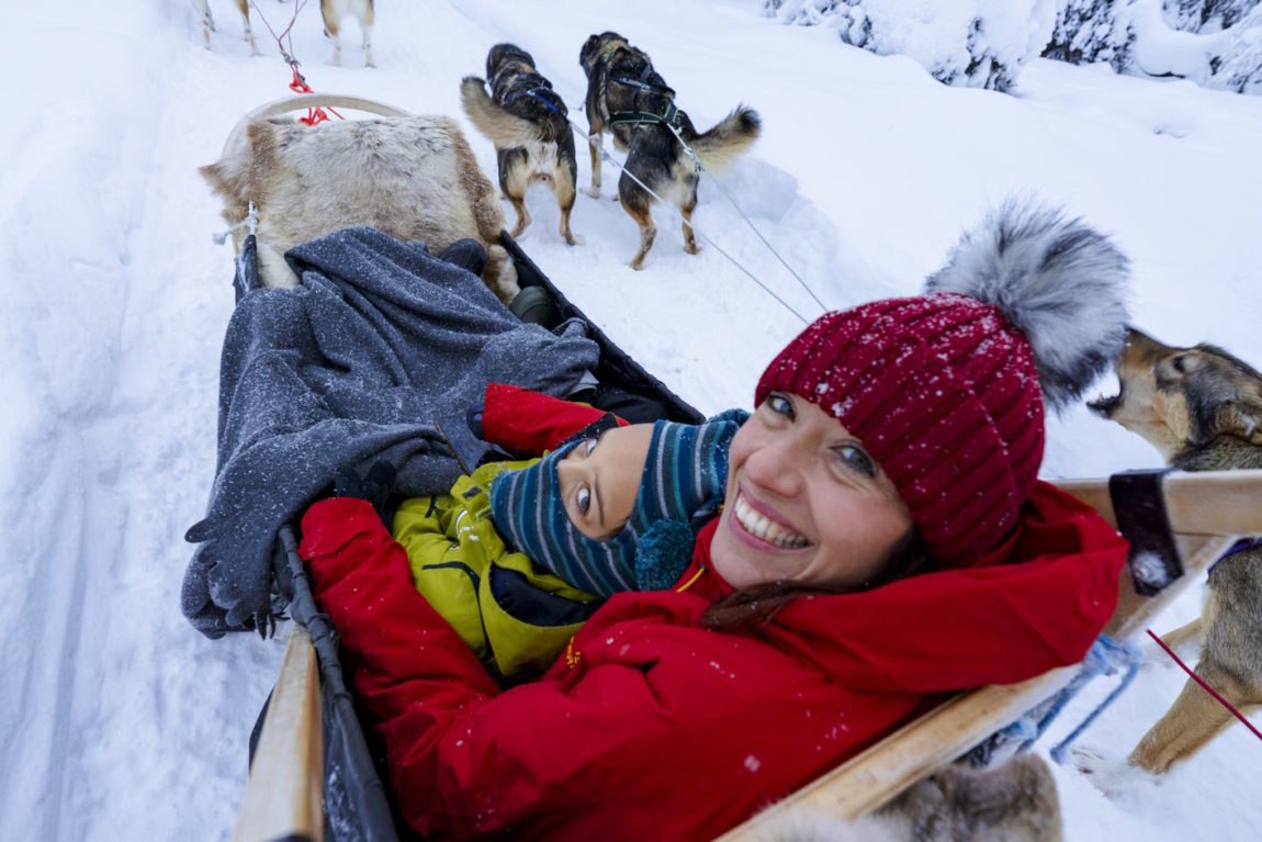 Happy woman with son dog sledding in Lapland, Finland. 