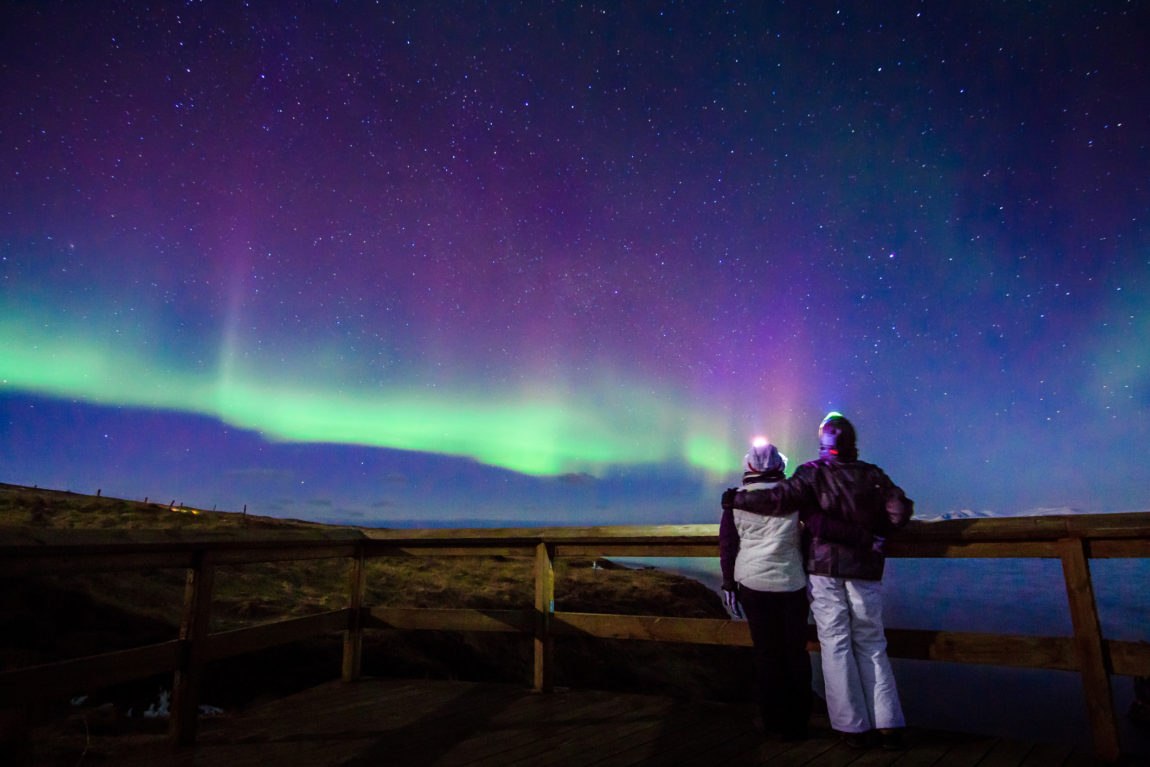 Young couple gazing at the Northern Lights in Iceland.