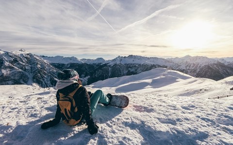 A snowboarder taking a rest on a New Zealand slope