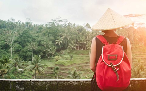 A woman in a rice field wearing a red backpack