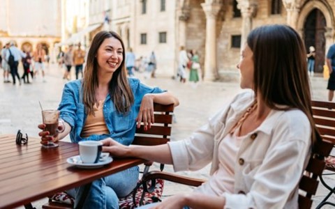 Two women sitting on a table drinking coffee