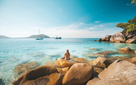 A person sitting on rocks in front of water