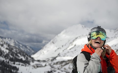 A person in the snow putting their helmet on