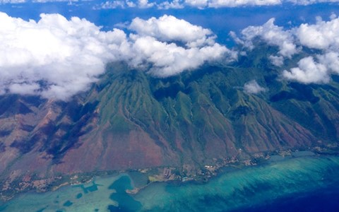 A mountain top in Hawaii with clouds covering the peak