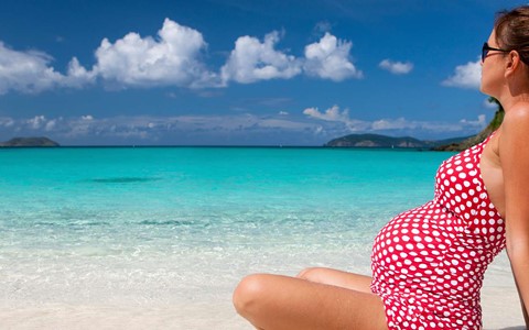 A pregnant woman sitting on a beach