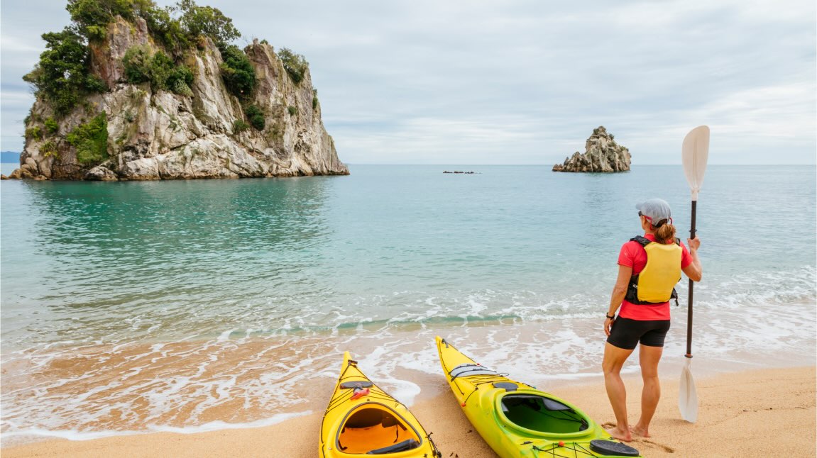 A person on a beach with kayaks